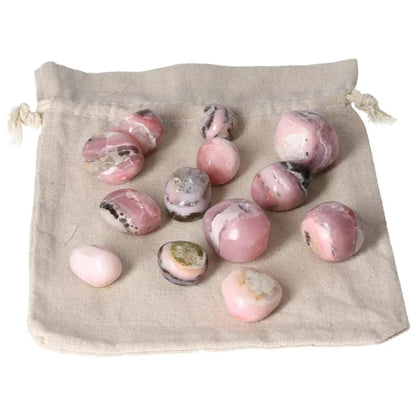 Pink Opal tumbled stones with pastel pink hues displayed on a cloth bag, known for emotional healing and calming energy.