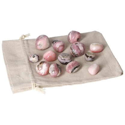 Pink Opal tumbled stones displayed on a cloth bag, showcasing soft pastel pink hues and smooth, soothing appearance.