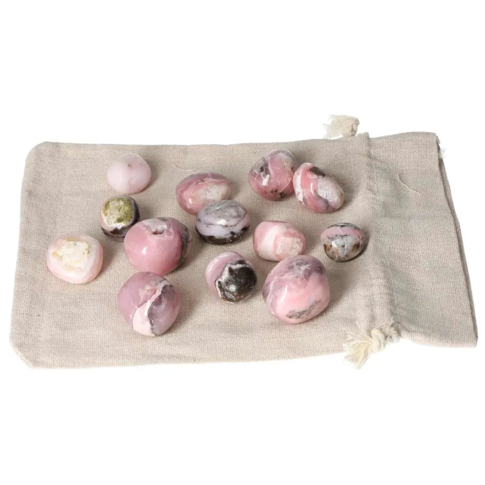 Pink Opal tumbled stones on beige cloth, showcasing their pastel hues and smooth texture, ideal for emotional healing and transformation.