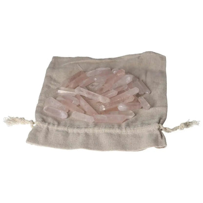Pink quartz small sticks displayed on a beige fabric pouch for healing and decoration.