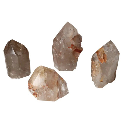 Four polished quartz crystals with hematite inclusions on a white background, showcasing Sylvia Crystals' premium craftsmanship.