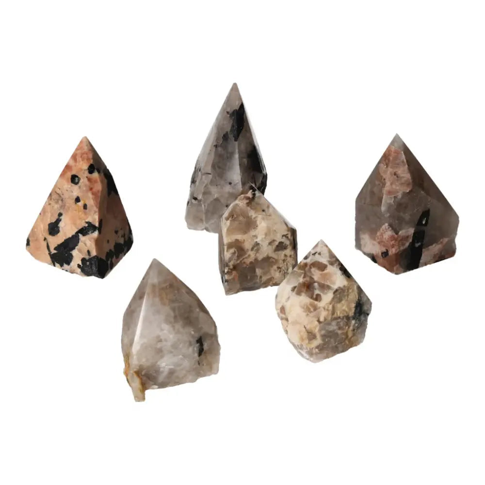 Group of polished point quartz crystals with black tourmaline inclusions, showcasing striking linear patterns.