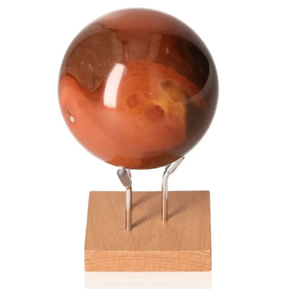 Polychrome Jasper Sphere displaying vibrant hues on a wooden stand, showcasing its unique banded patterns as a captivating centerpiece.