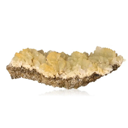 Prehnite druze gemstone featuring pale green to yellow hues, known for calming and enhancing spiritual growth, on a reflective surface.