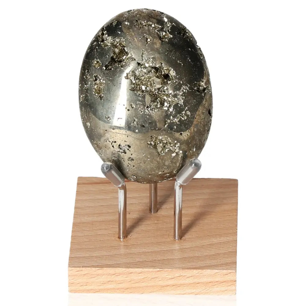 Pyrite palmstone M with golden hue and metallic luster, symbolizing prosperity, wealth, and success. Displayed on a wooden stand.