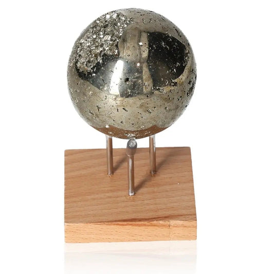 Pyrite sphere with metallic luster on a wooden stand, resembling gold, symbolizing abundance and prosperity.