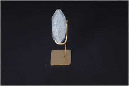 Clear Quartz Geometric Heart on a gold stand against a dark background, exemplifying purification and harmonizing energy properties.