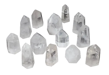 Collection of twelve clear quartz obelisks, each with unique shapes and clarity, displayed on a dark background.