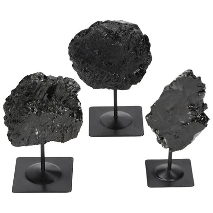 Rough black tourmaline stones on metal stands, protective and grounding crystals for energy stability by Sylvia Crystals.