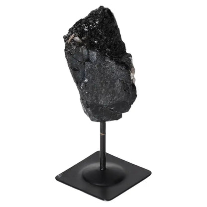Rough Black Tourmaline on metal stand by Sylvia Crystals, known for cleansing properties, ideal for harmony and positivity.