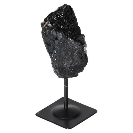 Rough Black Tourmaline on metal stand by Sylvia Crystals, known for cleansing properties, ideal for harmony and positivity.