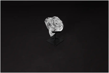 Rough clear quartz crystal on a sleek metal stand for purification and harmonizing energy spaces.