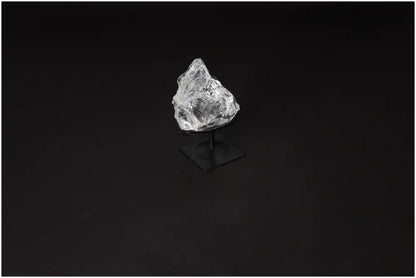 Clear Quartz crystal on metal stand, known for purification and energy harmonization, against dark background.