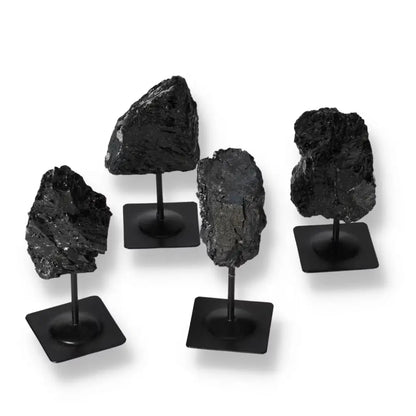 Rough Tourmaline stones on metal stands showcasing deep blacks and greens, from Sylvia Crystals, symbolizing luxury and spiritual harmony.