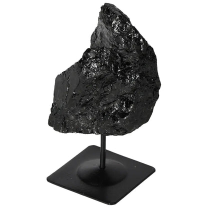 Rough black tourmaline crystal on a metal stand, showcasing its natural form and energy-balancing properties by Sylvia Crystals.
