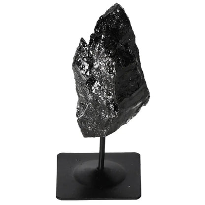 Rough black tourmaline crystal on metal stand for energy balance and natural decor.