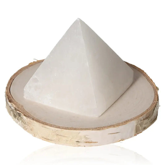 Selenite Pyramid 5cm with glass-like transparency on wooden base, known for purifying and soothing energy, perfect for peaceful ambiance.
