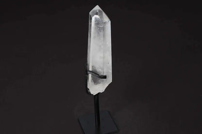 Semi polished clear quartz point on a stand, known for amplifying energy and clarity, ideal for meditation and energy work.