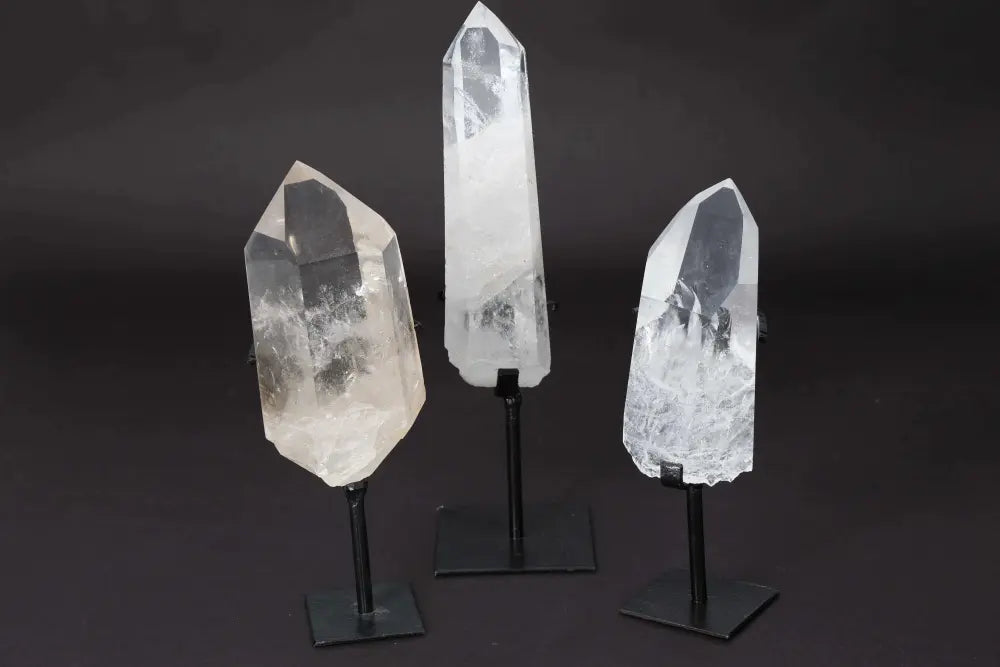 Three semi-polished quartz points on stands, showcasing their clarity and elegance, ideal for energy amplification and meditation.
