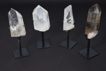 Four clear quartz points on stands for energy amplification and meditation, displayed on a dark background.