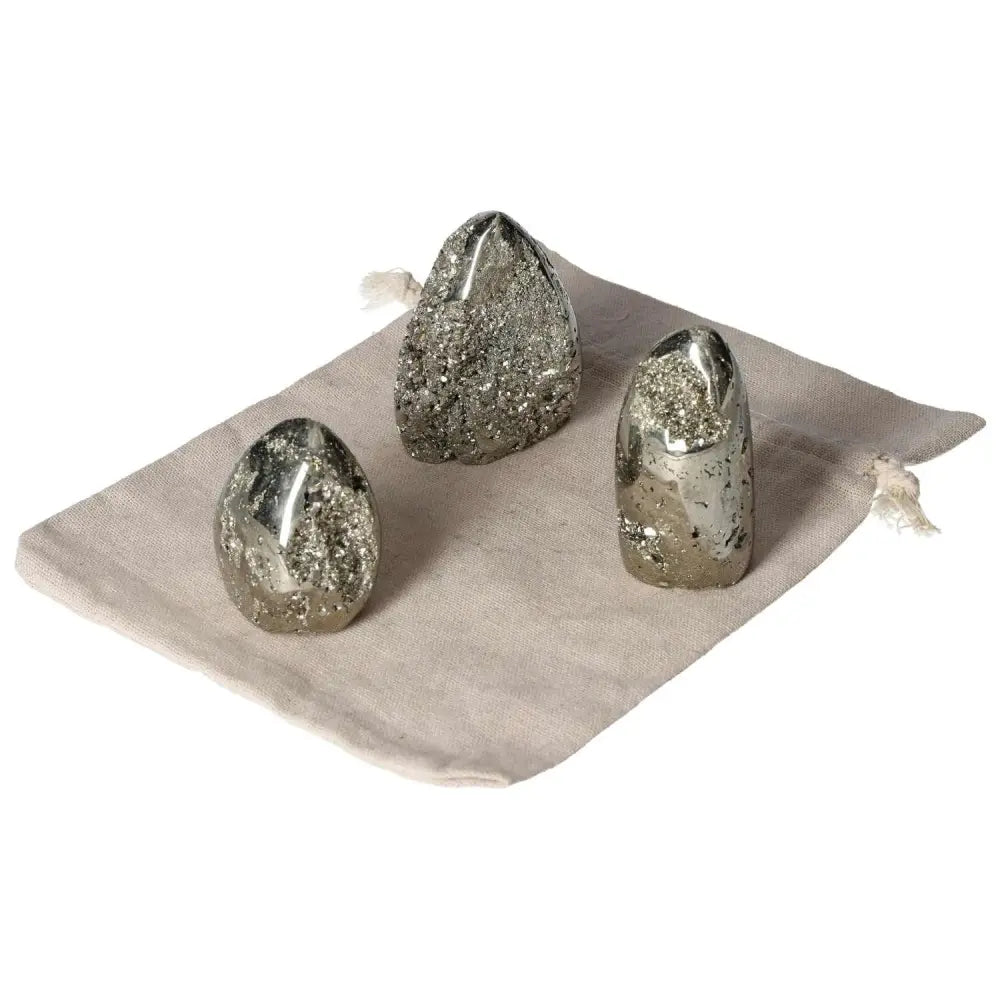 Three superior quality pyrite free form clusters on a cloth, showcasing geometric brilliance and metallic luster.