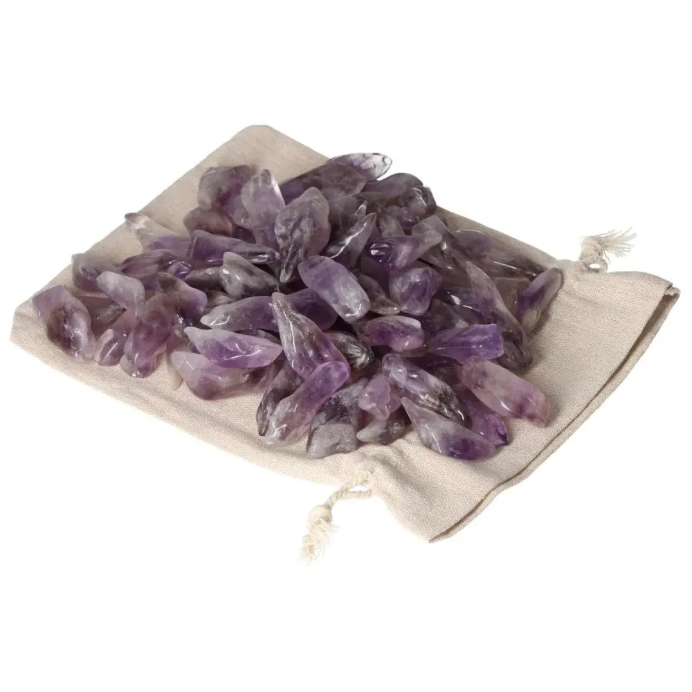 Tumbled Amethyst crystals on a beige fabric, showcasing vibrant purples and natural white veins from Sylvia Crystals.