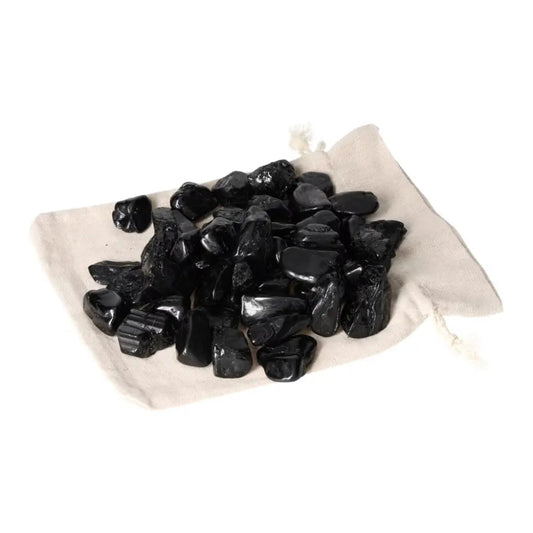 Pile of tumbled black tourmaline stones on a beige cloth, designed for grounding and protection by Sylvia Crystals.