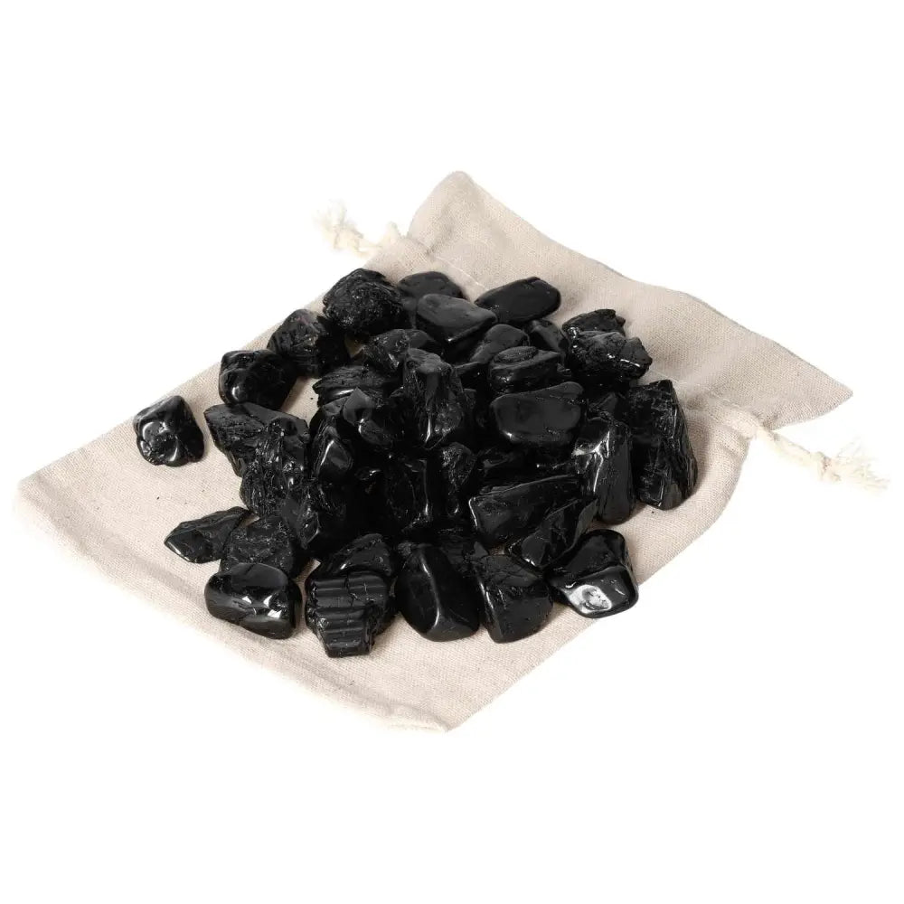 Tumbled Black Tourmaline crystals on a beige cloth bag, known for grounding and shielding against negative energies. Premium quality by Sylvia Crystals.