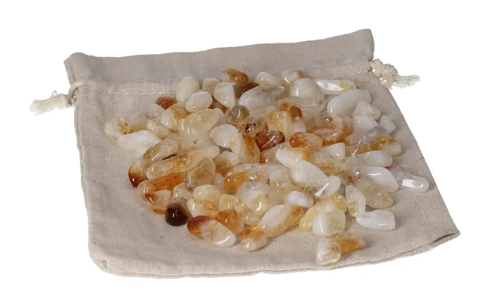 Tumbled Citrine and Quartz stones displayed on a beige drawstring pouch, symbolizing inspiration and material wealth.