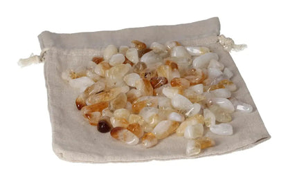 Tumbled Citrine and Quartz stones displayed on a beige drawstring pouch, symbolizing inspiration and material wealth.
