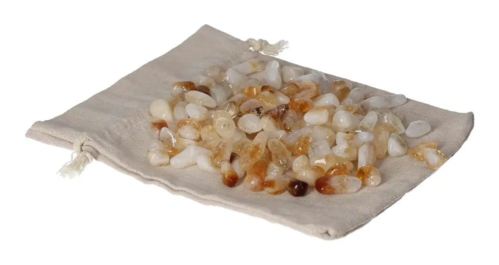 A collection of tumbled Citrine and Quartz stones displayed on a beige cloth, symbolizing inspiration and abundance.