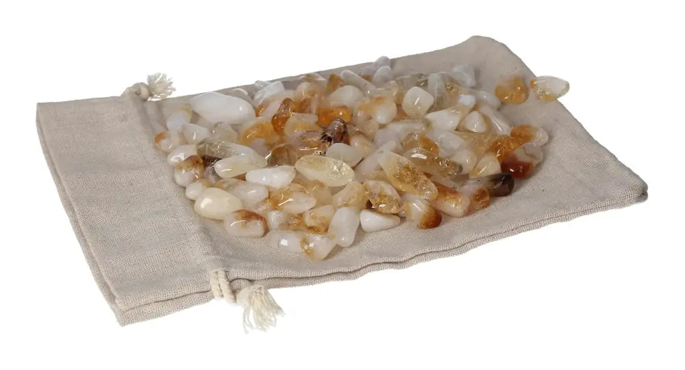 Tumbled citrine with quartz stones on a beige pouch, symbolizing inspiration, energy, and abundance.
