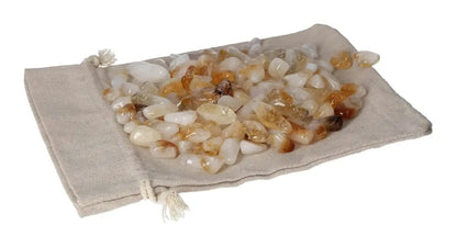 Tumbled citrine with quartz stones on a beige pouch, symbolizing inspiration, energy, and abundance.