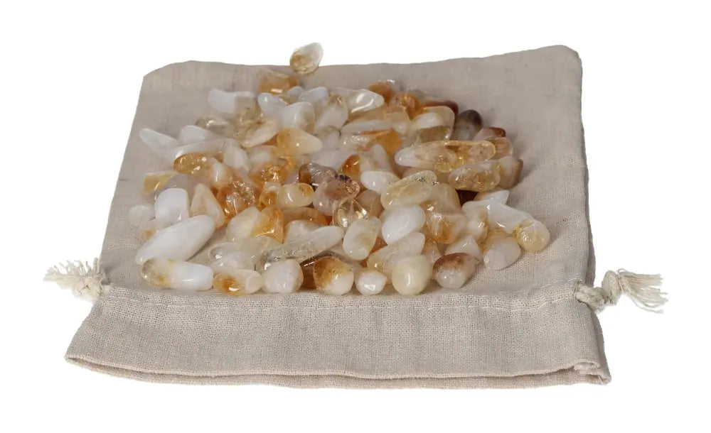 Tumbled citrine and quartz stones on a beige cloth bag, symbolizing inspiration and abundance for new ventures.