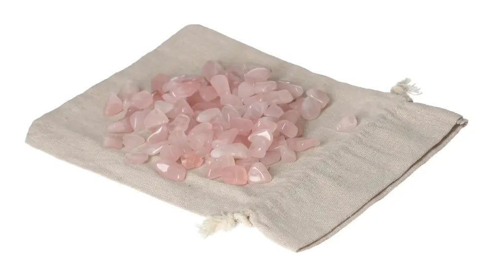Tumbled Rose Quartz stones displayed on a beige cloth bag, symbolizing love and emotional healing with their gentle, pink hues.