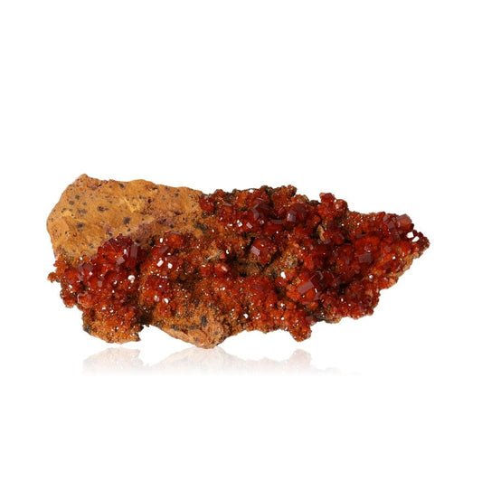 Vibrant hexagonal Vanadinite crystals with reddish-brown hues on a glassy surface, known for enhancing focus and personal transformation.