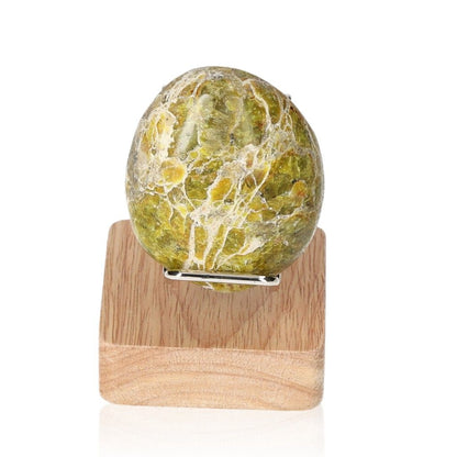 Green Jasper Palmstone on wooden stand showcasing its healing and rejuvenating properties.