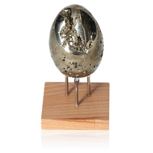 Polished pyrite egg on a wooden stand, known for enhancing independence and encouraging new ideas and goal achievement.