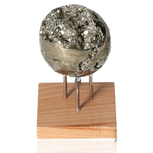 Sparkling pyrite sphere on wooden stand, symbolizing independence, courage, and motivation for personal growth and success.