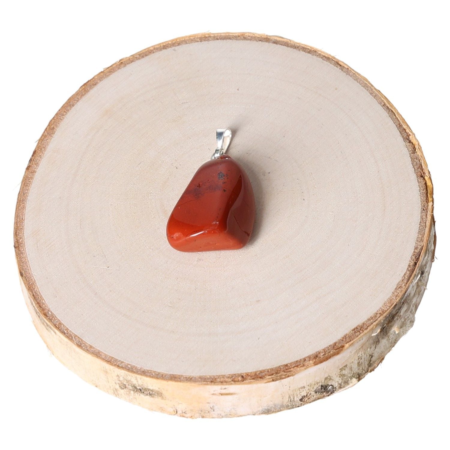 Jasper red tumbled pendant displayed on a wooden base, showcasing its polished stone and silver loop design.