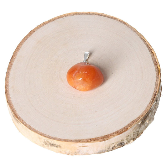 Carnelian tumbled pendant on wooden display, showcasing its vibrant orange hue and smooth polished finish.