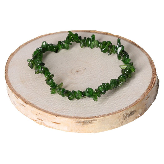 Green diopside bracelet chips on wooden display, showcasing vibrant gemstone jewelry.