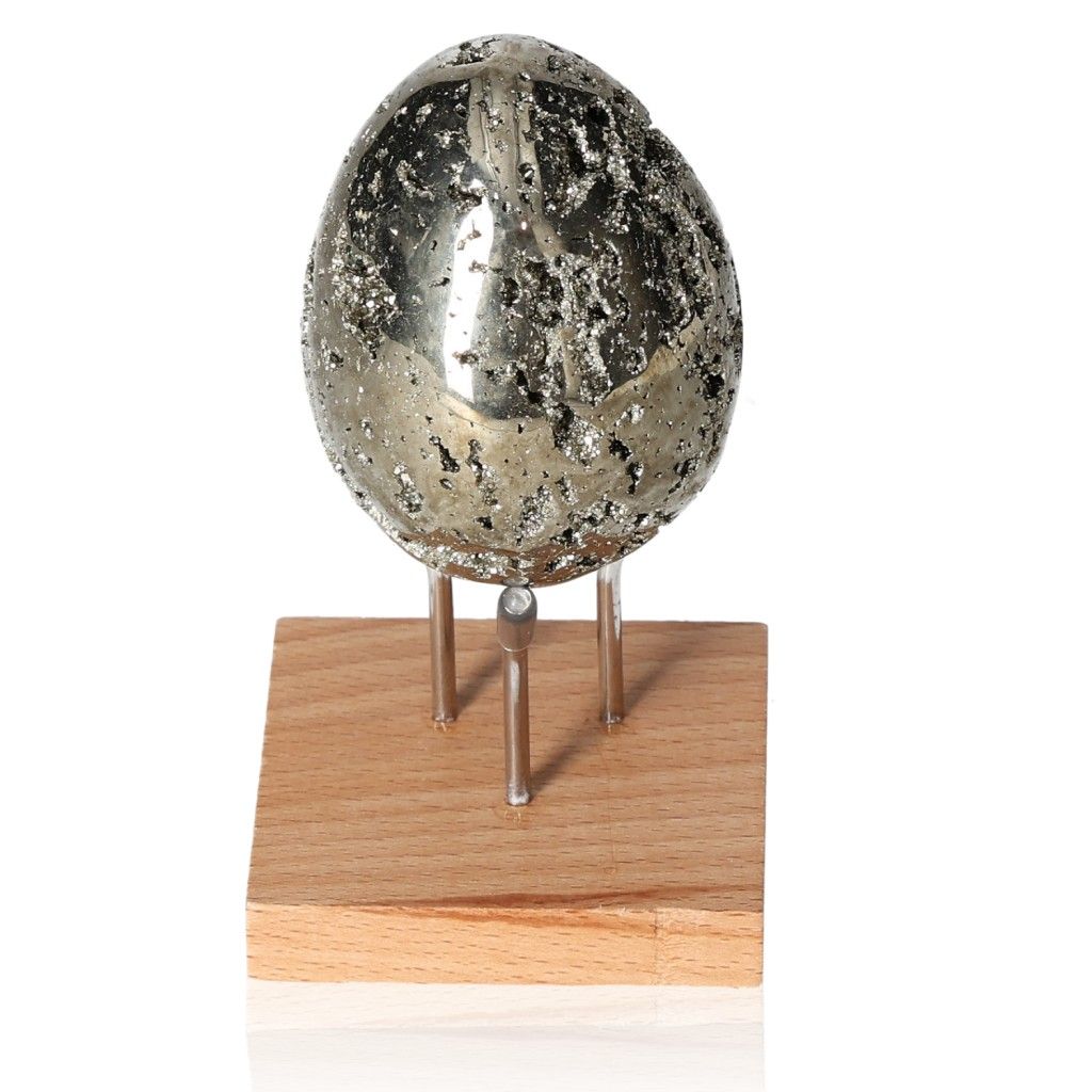 Sparkling pyrite egg on wooden stand, inspires new ideas and independence, enhances courage and motivation for achieving goals.