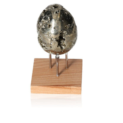 Pyrite egg on wooden stand, promoting independence and courage for personal growth and goal achievement.