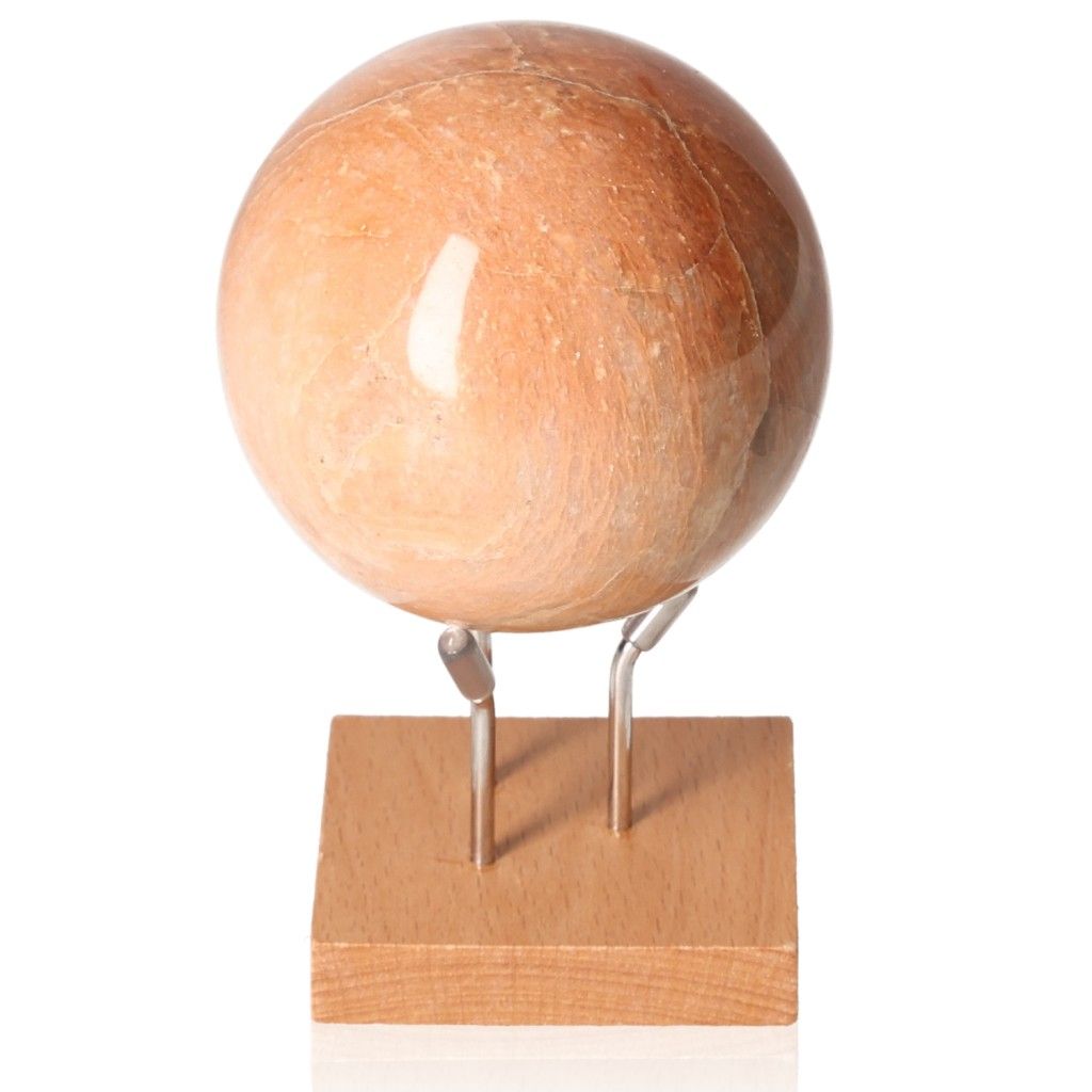 Peach Moonstone Sphere on wooden stand, showcasing its soft peach hue and smooth surface, ideal for emotional healing and inner peace.