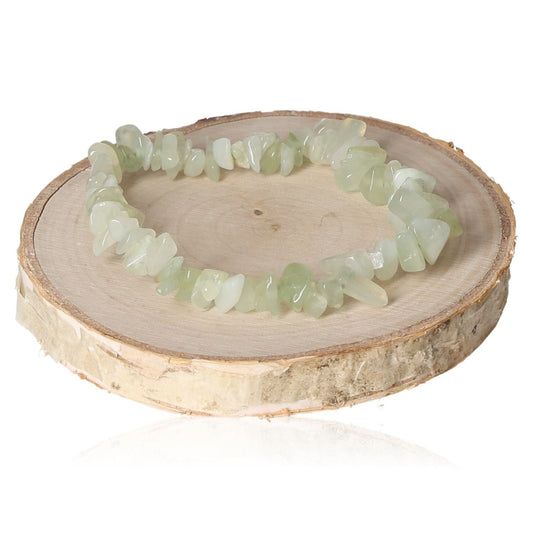 Serpentine bracelet chips displayed on a wooden slice, showcasing natural green stone beads for stylish jewelry lovers.