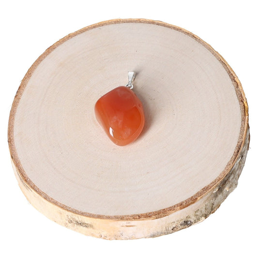 Carnelian Botswana tumbled pendant on wooden slice, showcasing its rich orange tones and elegant silver bail.