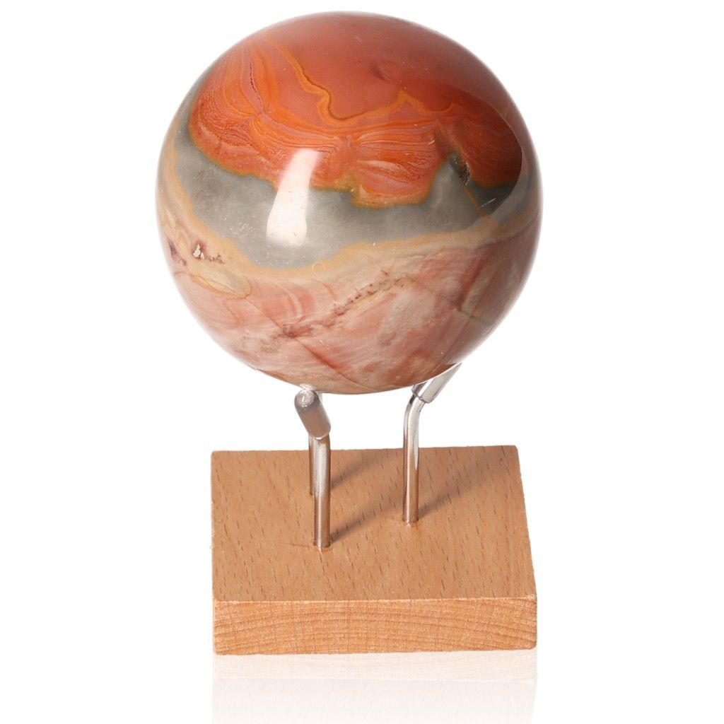 Polychrome Jasper Sphere with vibrant red, orange, and brown banded patterns on a wooden stand, known for grounding and energizing properties.