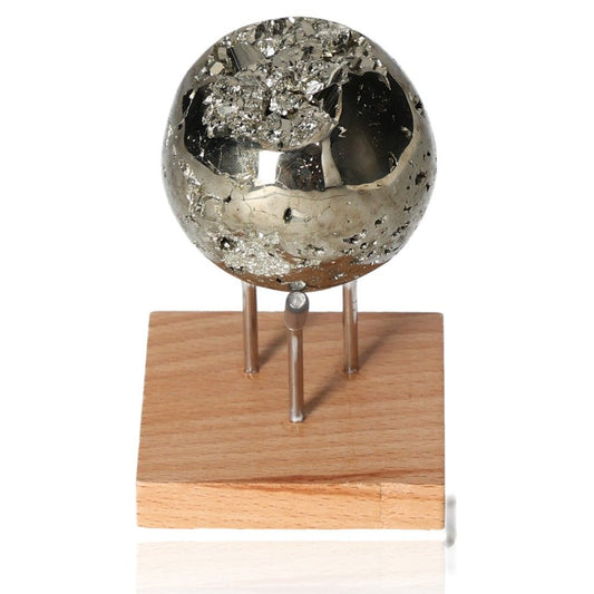 Shiny pyrite sphere on wooden stand, promoting courage and initiative development.