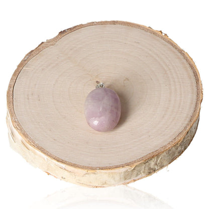 Kunzite tumbled pendant displayed on a wooden slice.